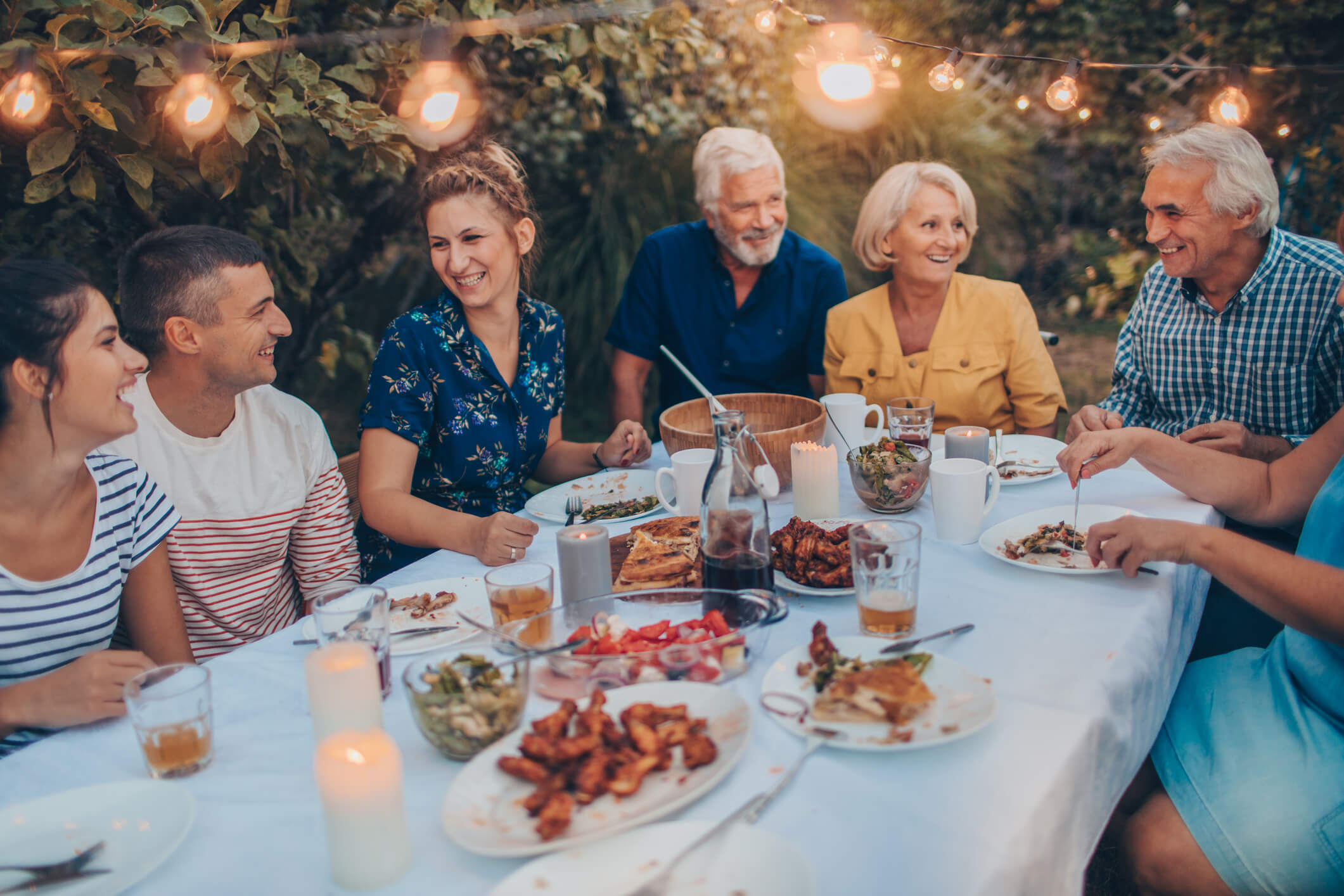 Multi-generational family eating together outside